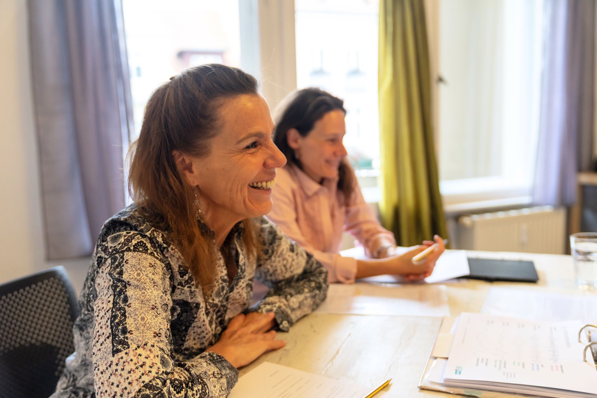 Friederike Gerling und eine Kollegin lachen gemeinsam am Seminartisch