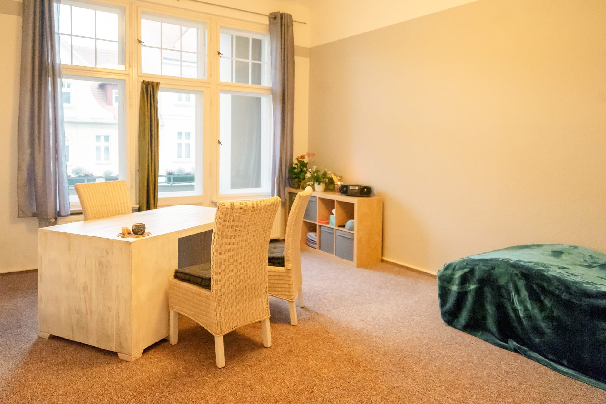 Heller Praxisraum mit Schreibtisch, Stühlen und einer Liege