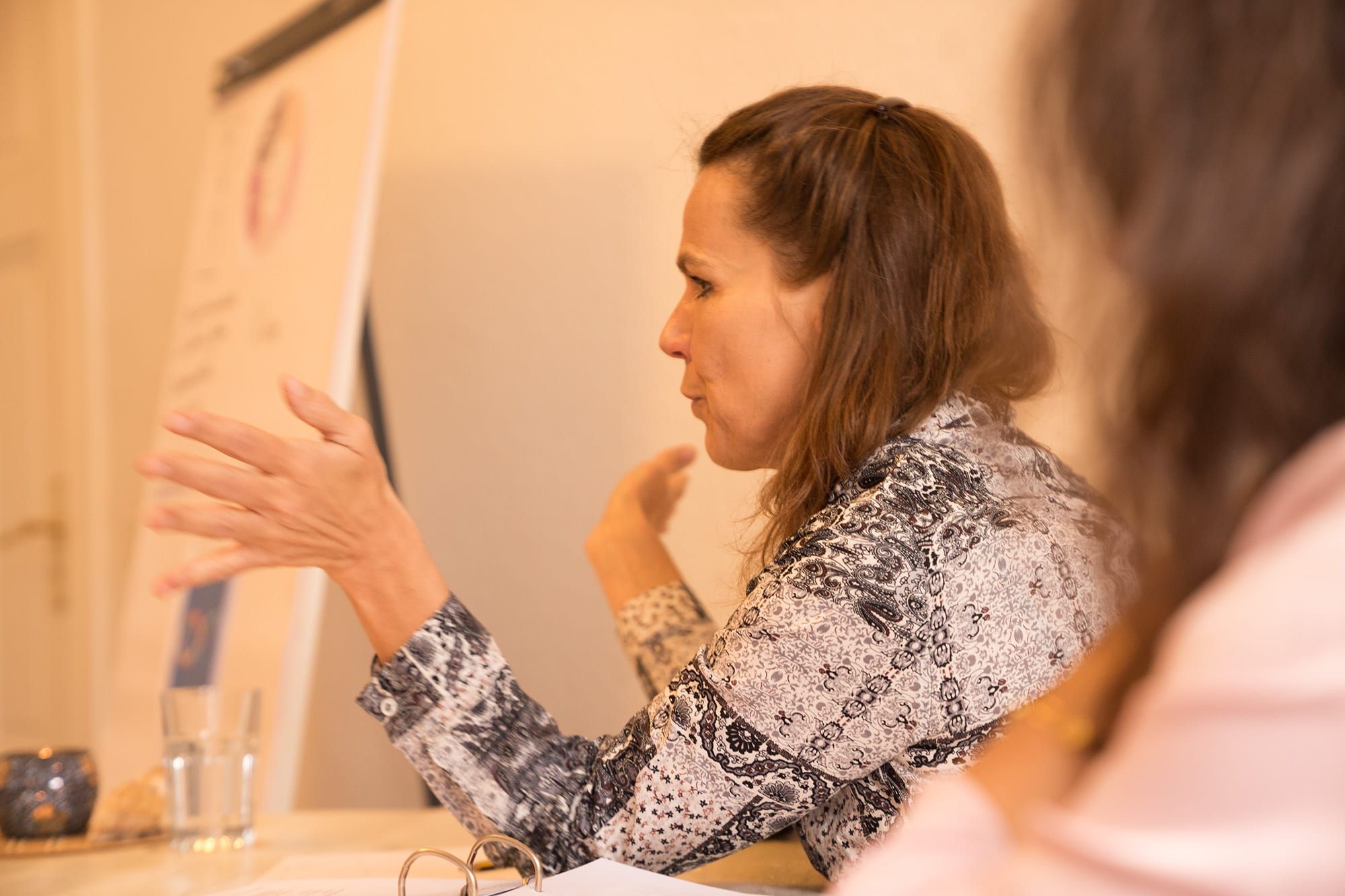 Friederike Gerling erklärt mit Gesten im Seminarraum, im Vordergrund ein Flipchart